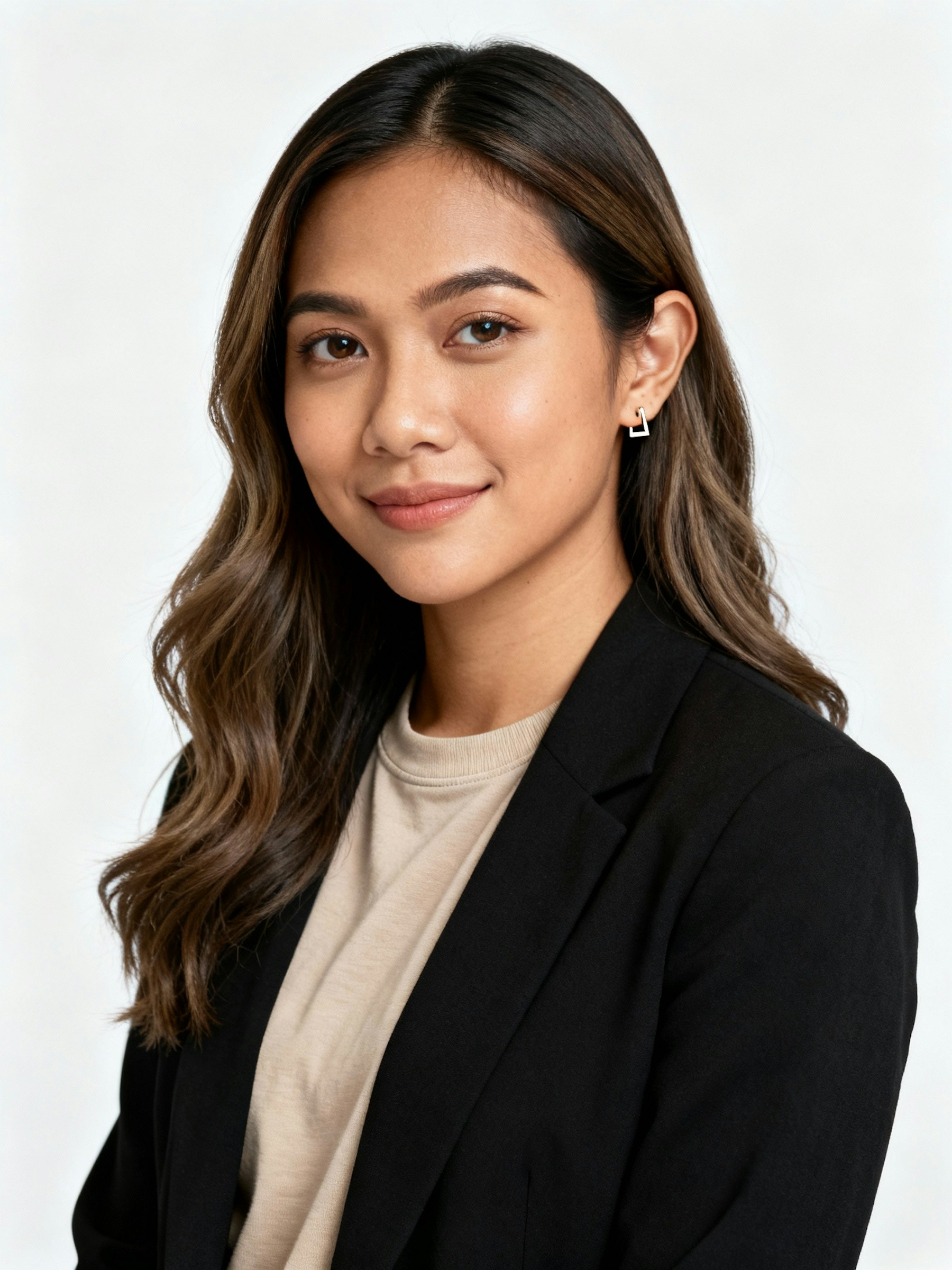 Professional portrait of a woman with wavy brown hair, wearing a black blazer and beige top, smiling warmly against a light background.