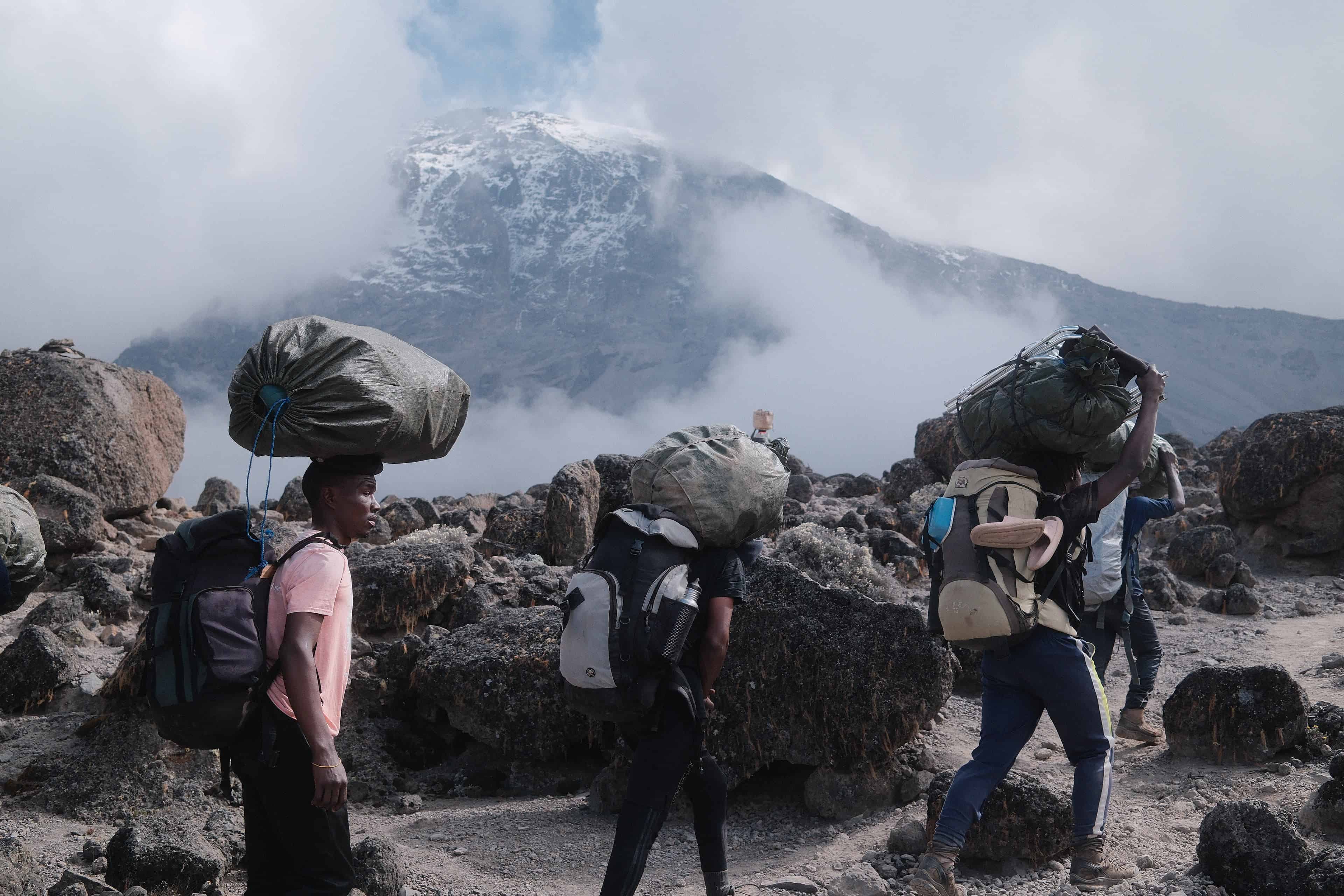 Legend Expeditions Kilimanjaro mountain crew of guides, cook, and porters walking to high camp on Kilimanjaro.