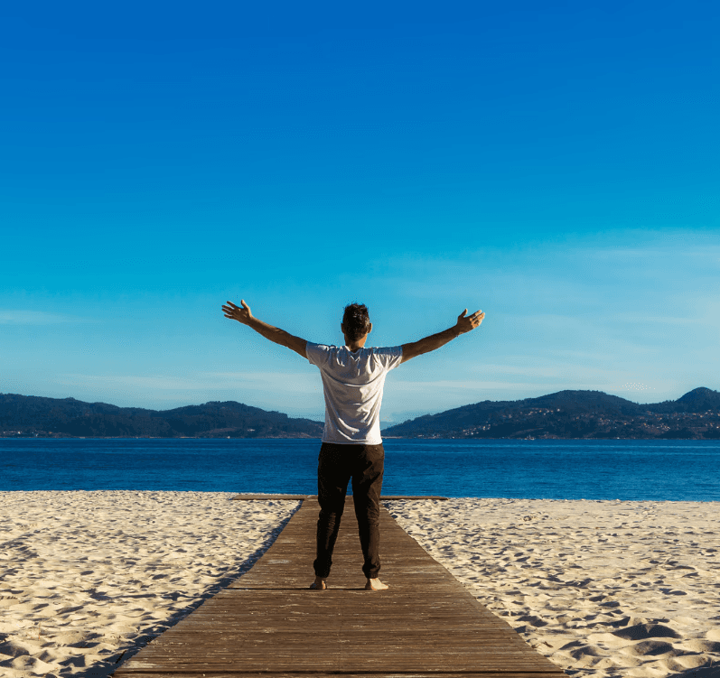 A person with curly hair sits at a desk, working on a laptop in a cozy, well-lit environment.