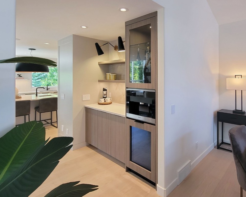 A beverage station with a fridge and a coffee maker. Lots of open shelving and custom millwork.