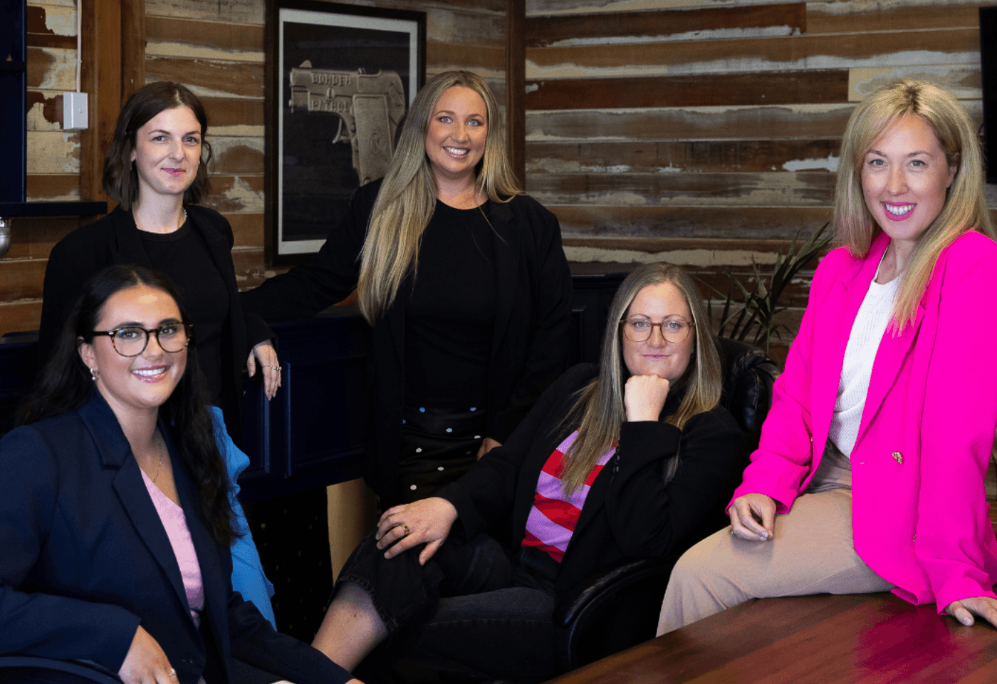 Team of five people standing together in a modern office