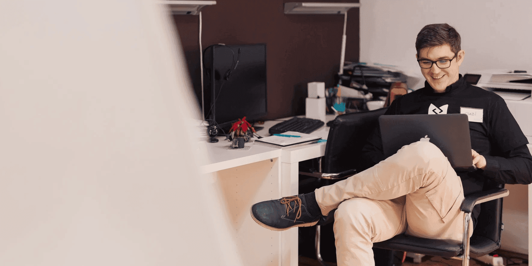 Man working from chair with laptop in office for recruiters showing remote flexibility