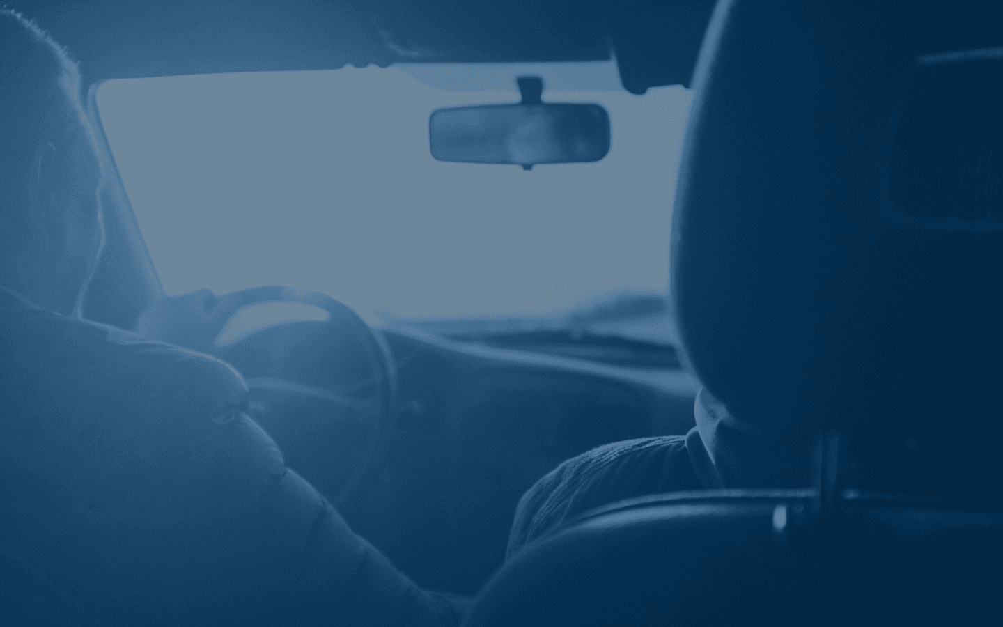 Person relaxing in their car with their feet resting out of the window, renewing their vehicle licence on their phone.