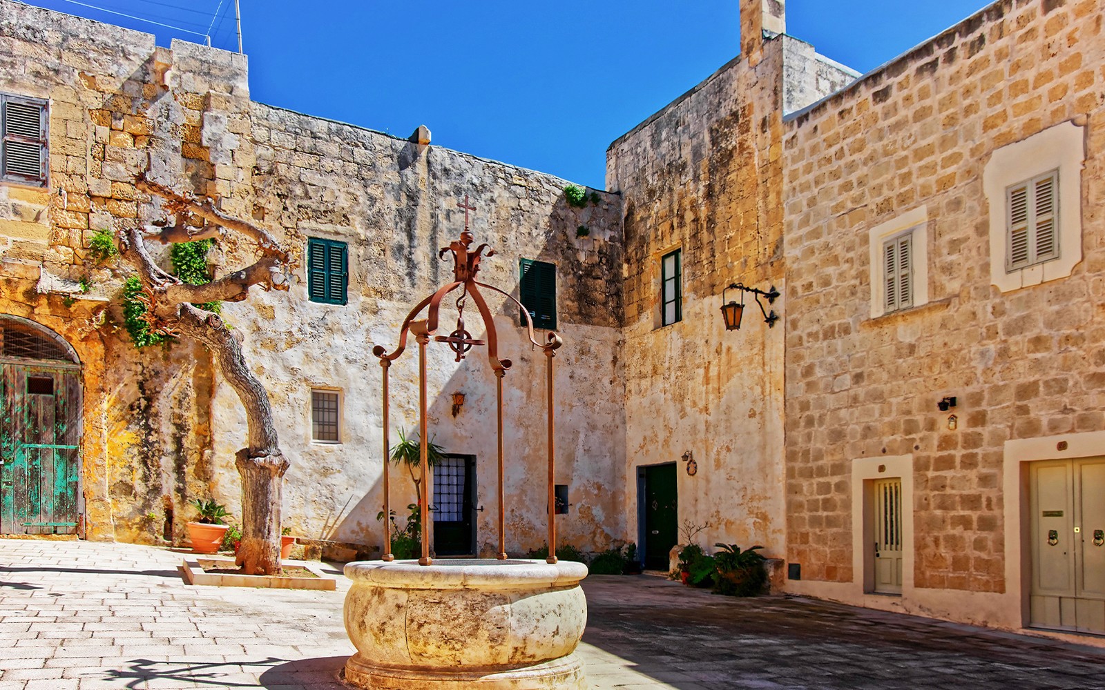 Historic courtyard in Mdina with stone walls and an old well, Malta.
