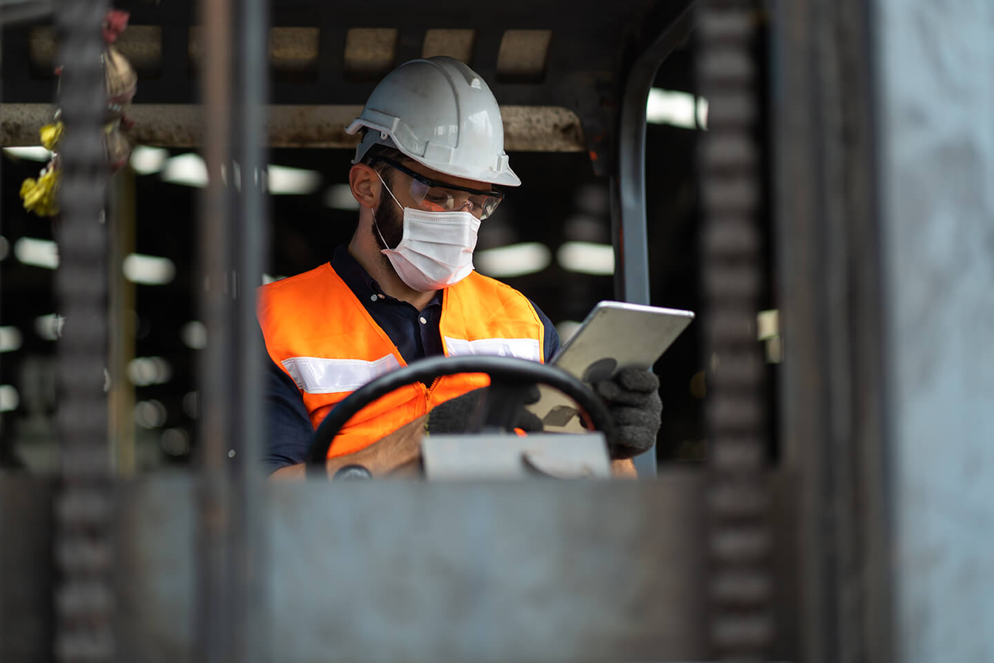 Worker in safety gear using a tablet at an industrial site