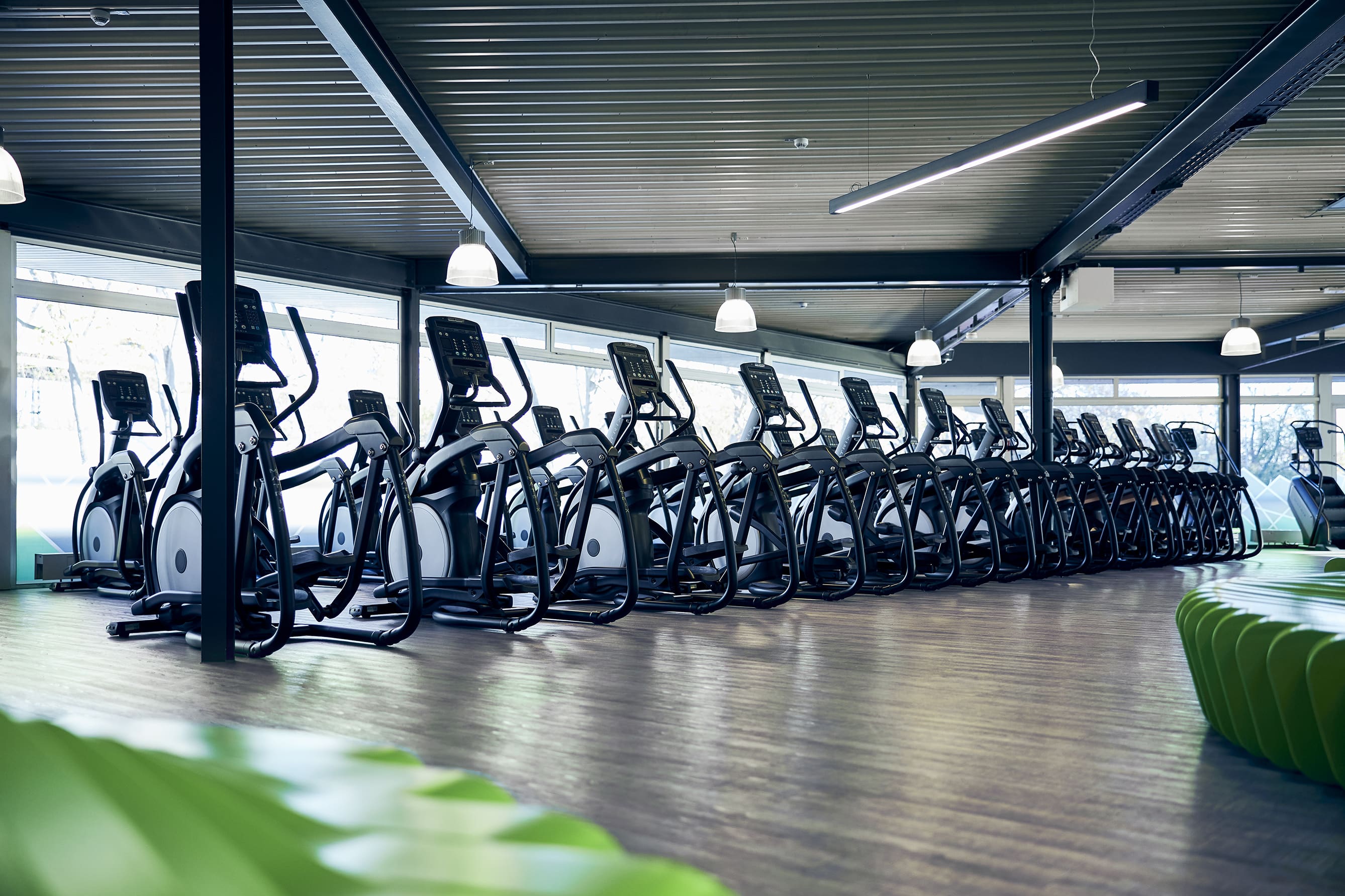 Reihe von Crosstrainern im XTRAFIT Fitnessstudio in Köln-Ehrenfeld mit großen Fenstern.