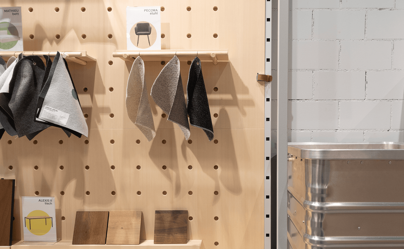 Detailaufnahme einer Holz-Lochwand mit Lederriemen, die flexibel in das modulare Regalsystem des micasa Stores integriert werden kann.