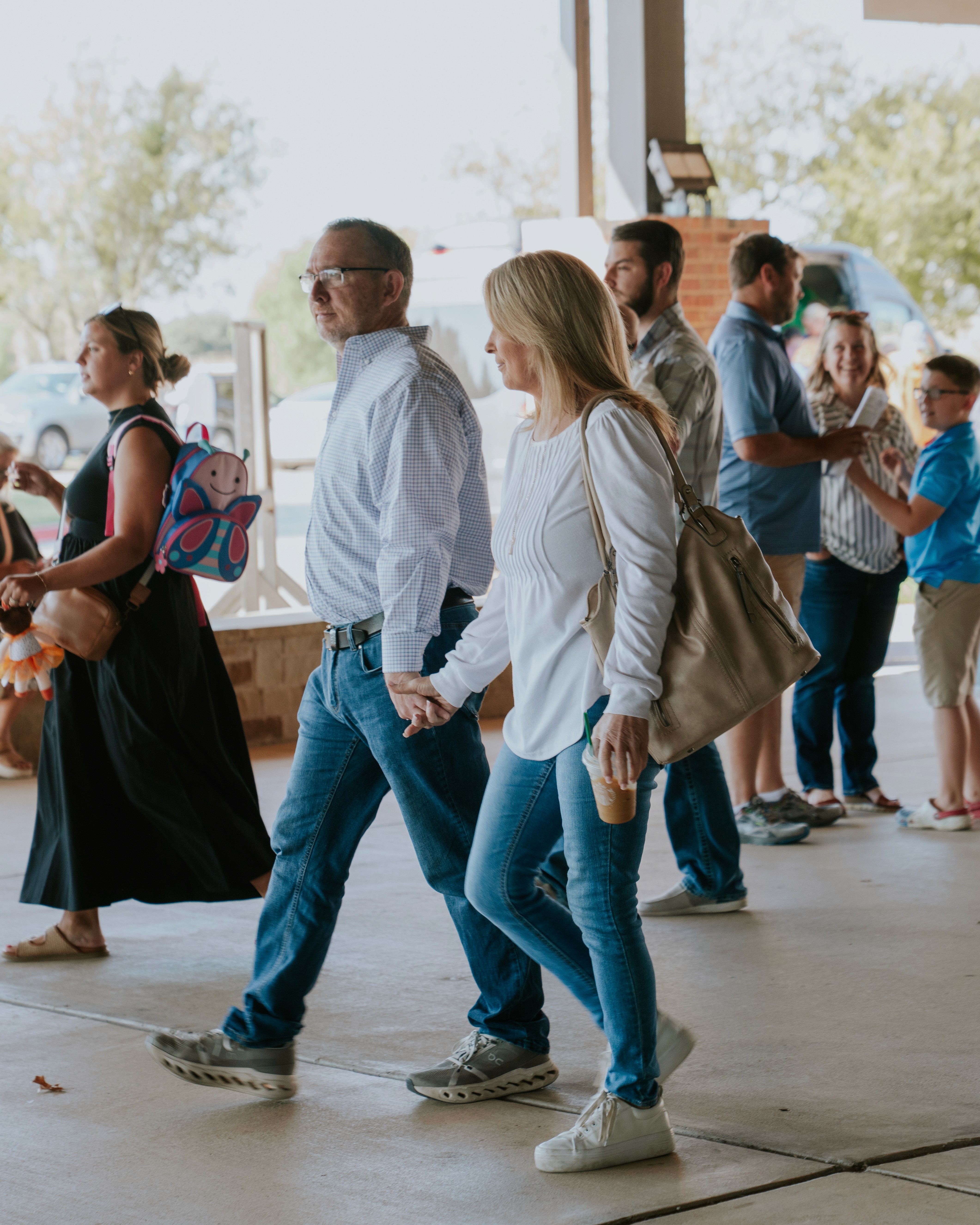 People walking and talking in a spacious indoor area with modern decor and glossy wooden floors.