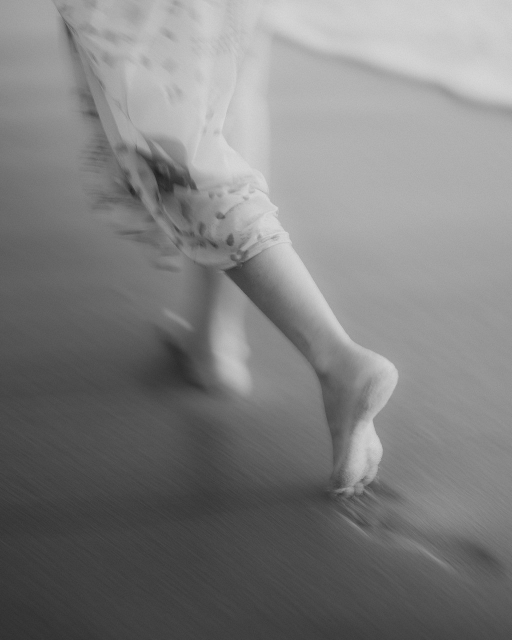 Bare feet walking on a wet sandy beach.