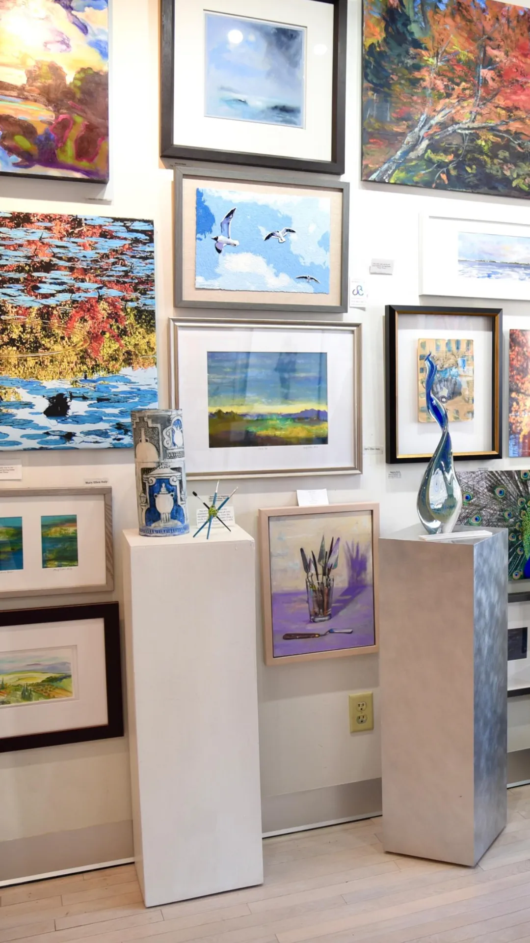 Interior view of an art gallery with an array of paintings and sculptures exhibited for public viewing.