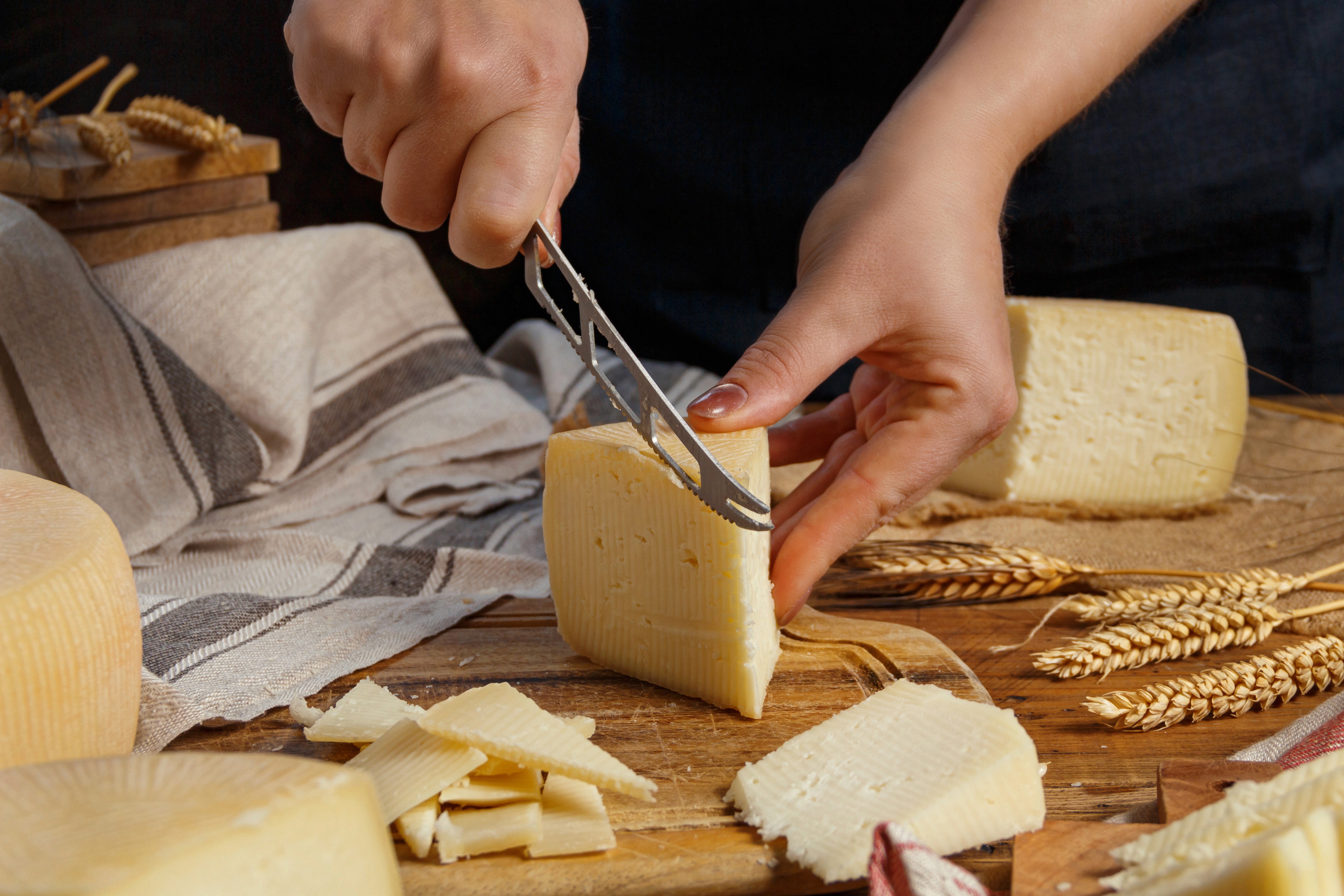 Close-up of a person slicing a fresh eggplant on a wooden table outdoors.