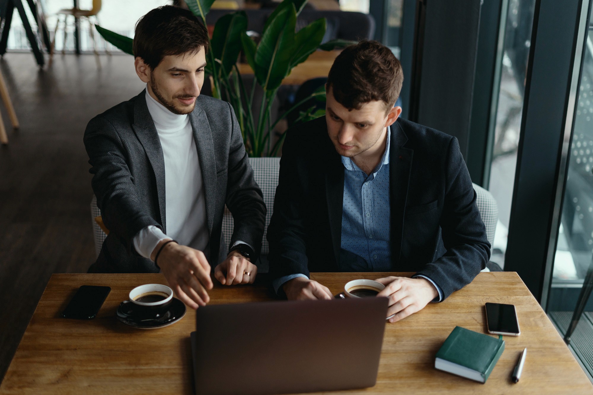 Two businessmen pointing at the laptop screen while discussing possible business ideas in Dubai.