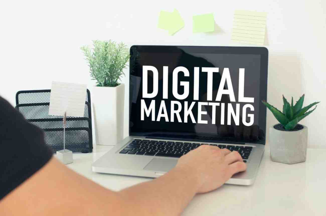 Person with hand on his laptop and the word digital marketing is written on the laptop screen