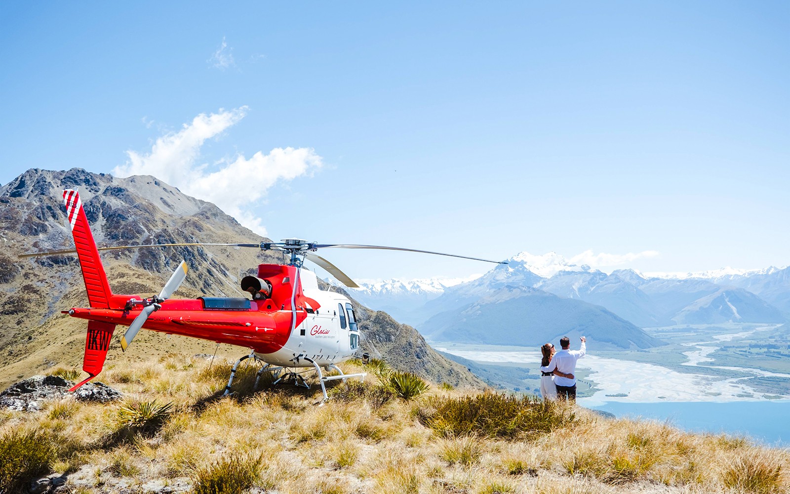 Par ved helikopter på Queenstown utsiktspunkt med utsikt over fjell og elvedal.