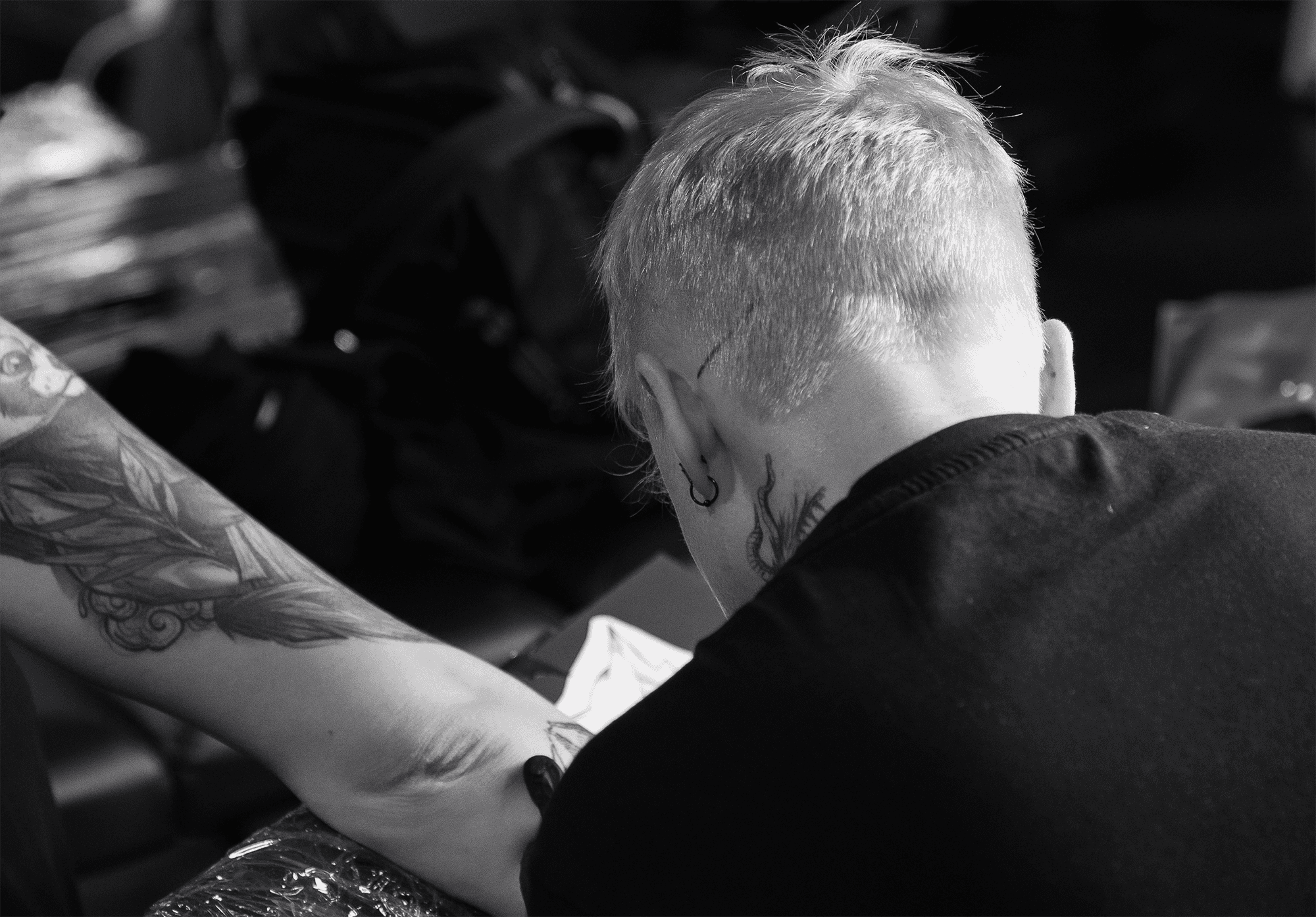 Looking over the shoulder of an artist tattooing an arm