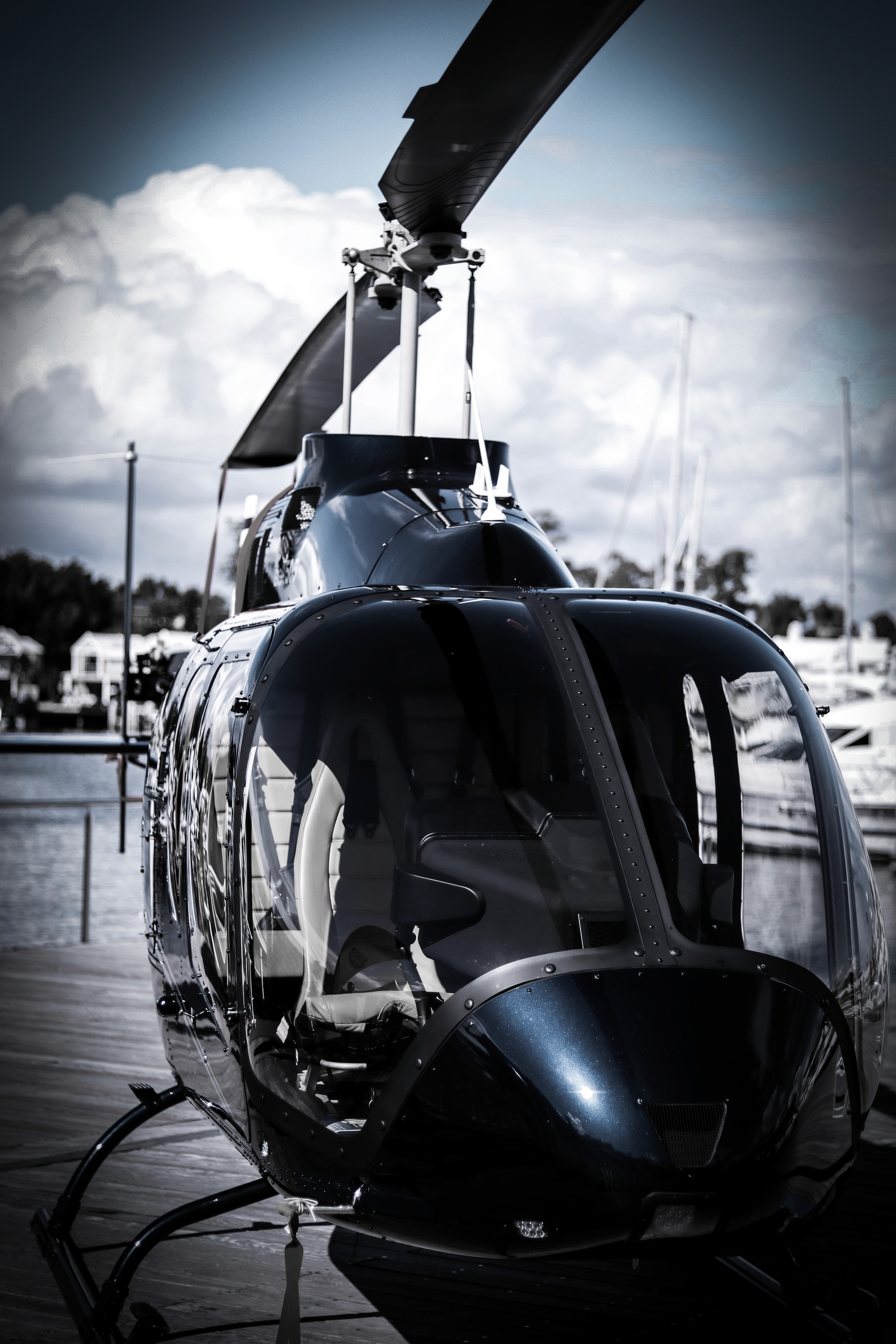 Schwarzer Hubschrauber steht am Dock, im Hintergrund ist bewölkter Himmel zu sehen, die Rotorblätter sind deutlich erkennbar.