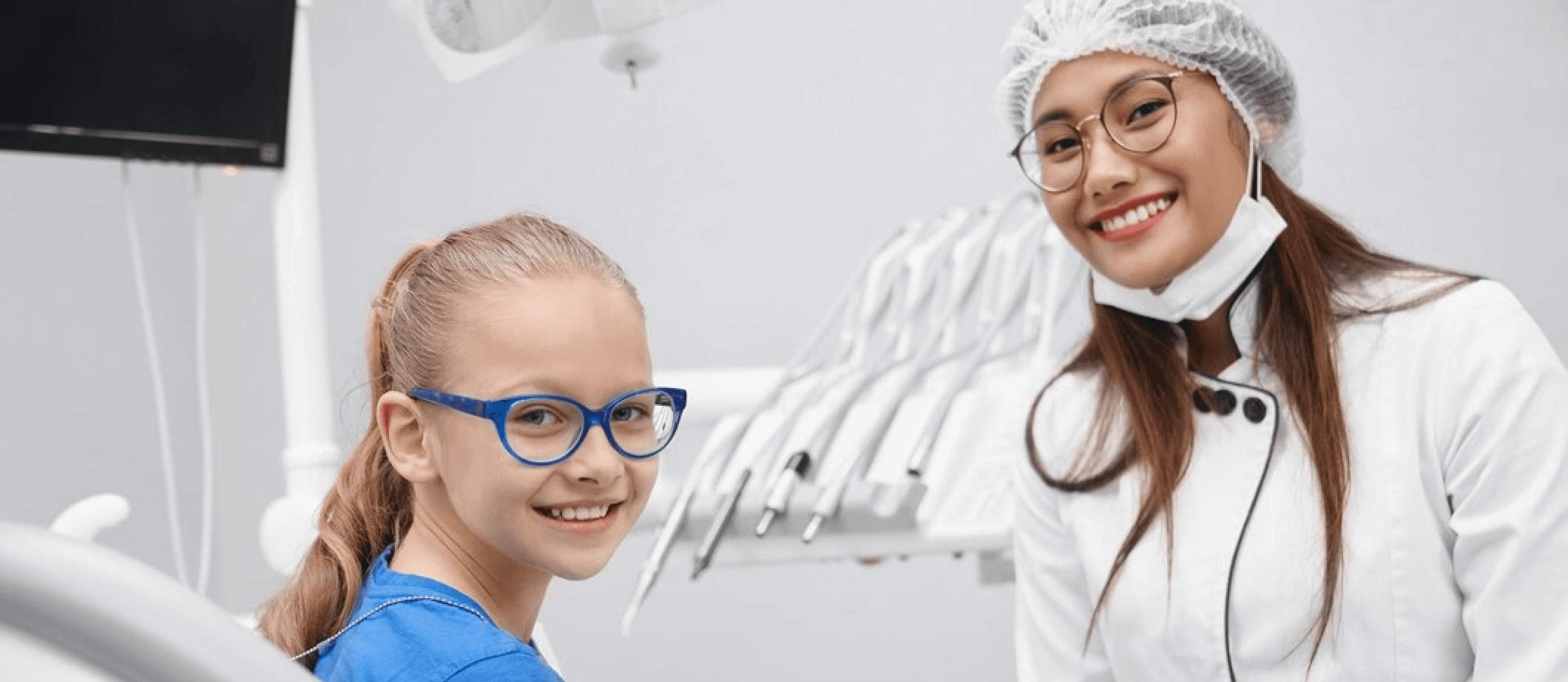 smiling children with glasses sitting in a dental clinic, looking happy and confident after their dental visit.