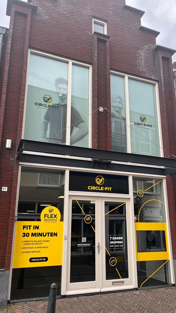 A Circle Fit hub with large glass windows and a yellow sign, displaying the entrance and business name prominently.