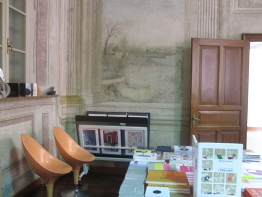 A photo of a table filled with books and two orange, egg shaped chairs.