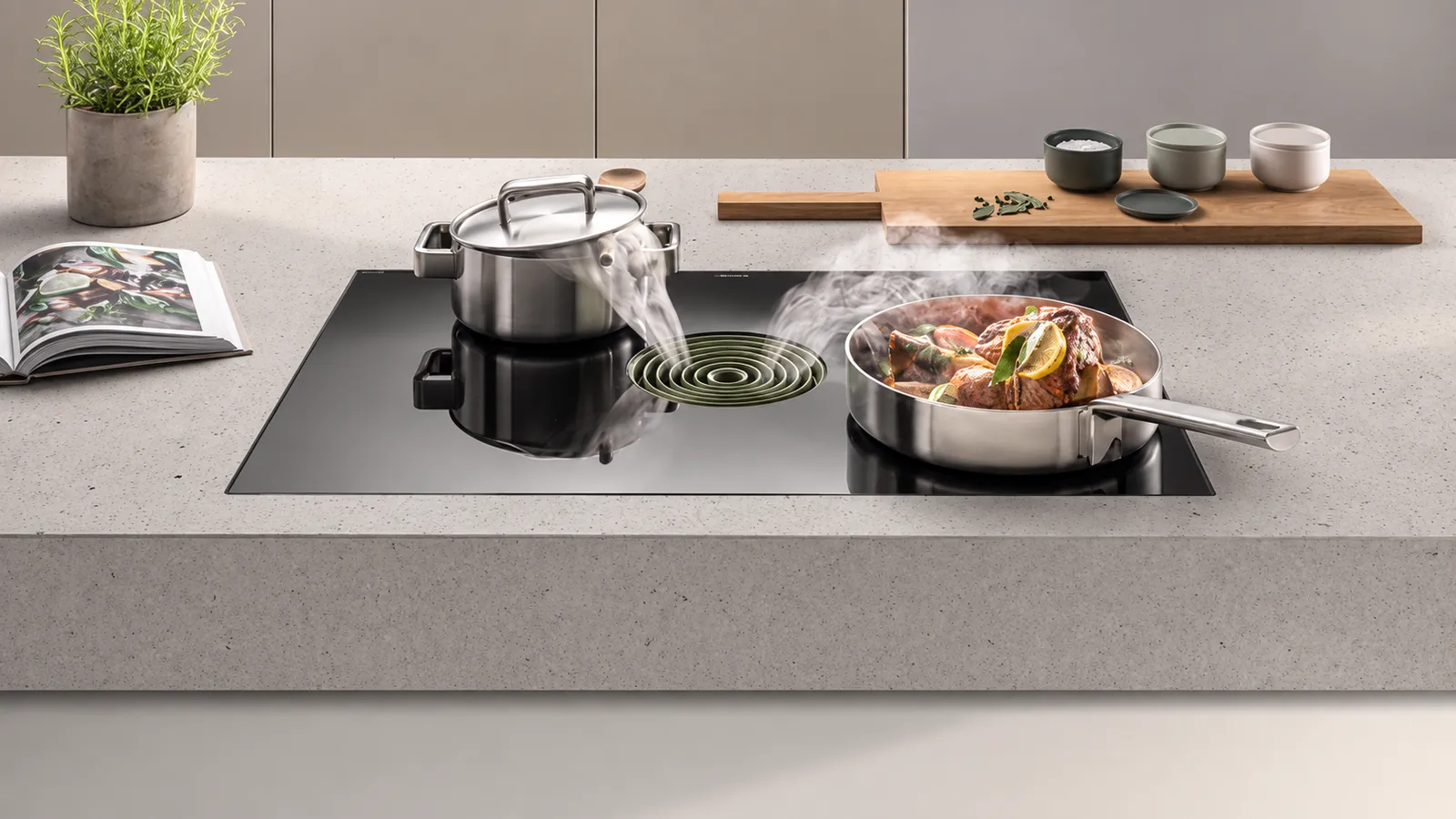 Table de cuisson avec aspiration centrale, casserole et poêle sur un plan de travail clair