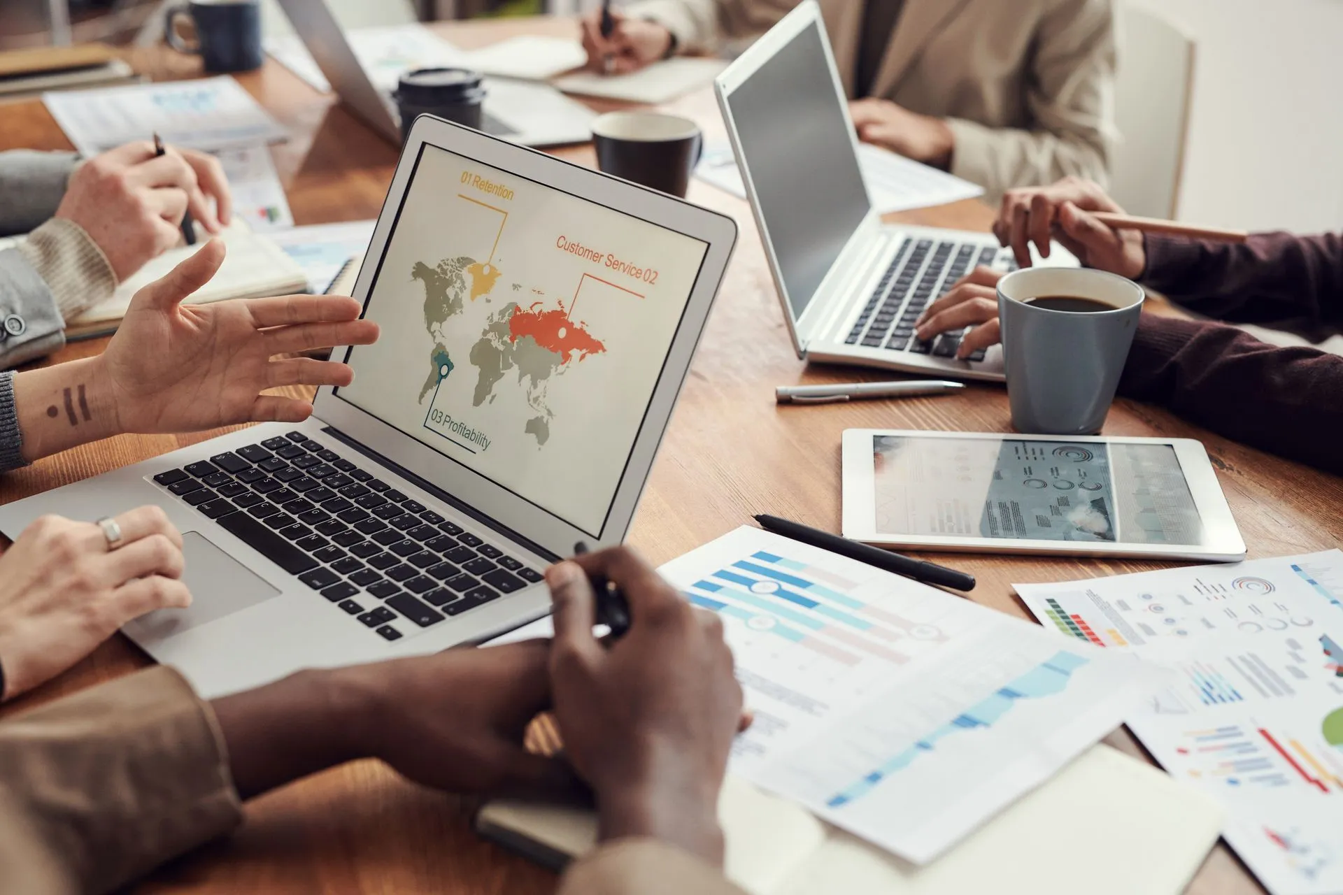 Team reviewing business charts on a laptop and tablet during a meeting
