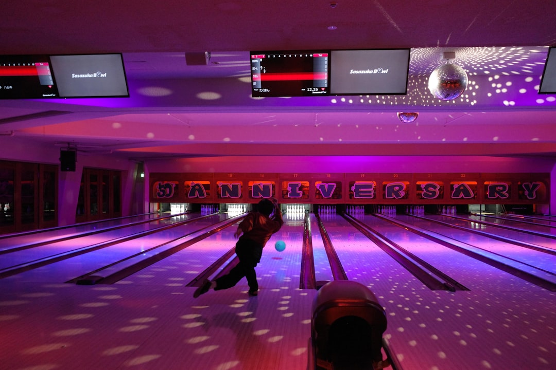 Person bowling in a colorful, dimly lit alley.