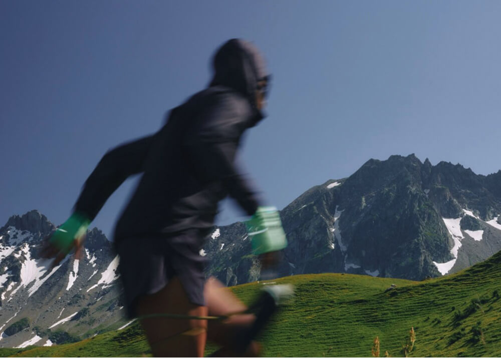Person running outdoors with mountains in the background.