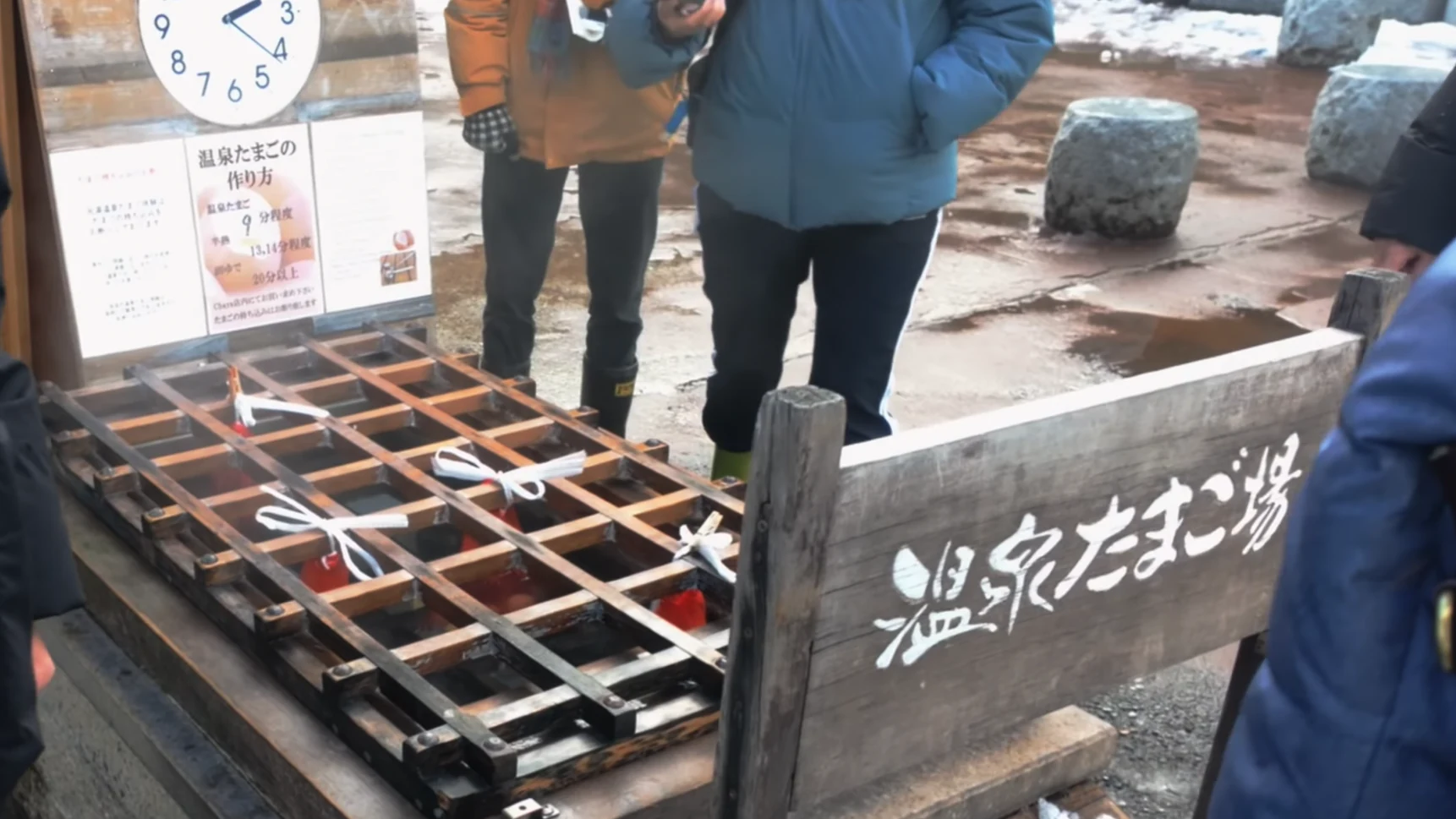 Visitors in winter coats waiting beside the hot spring egg-boiling pit in Kinosaki.
