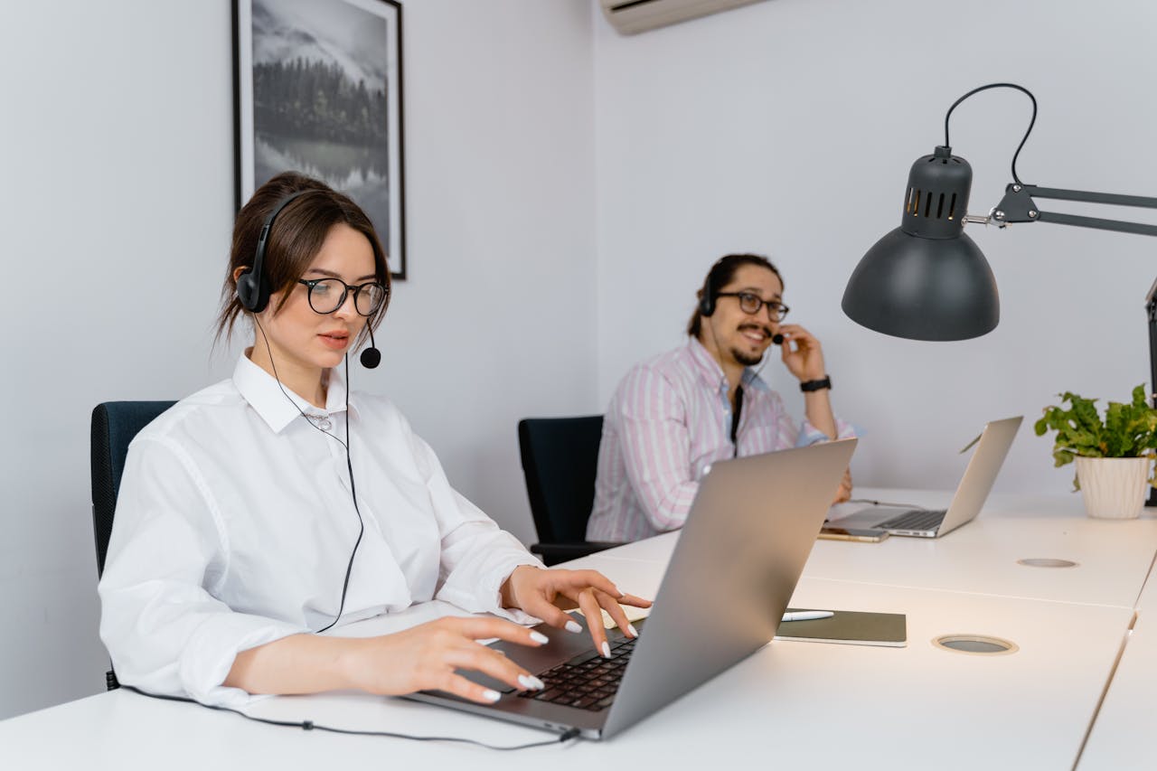 a woman sitting in front of a computer talking on a cell phone