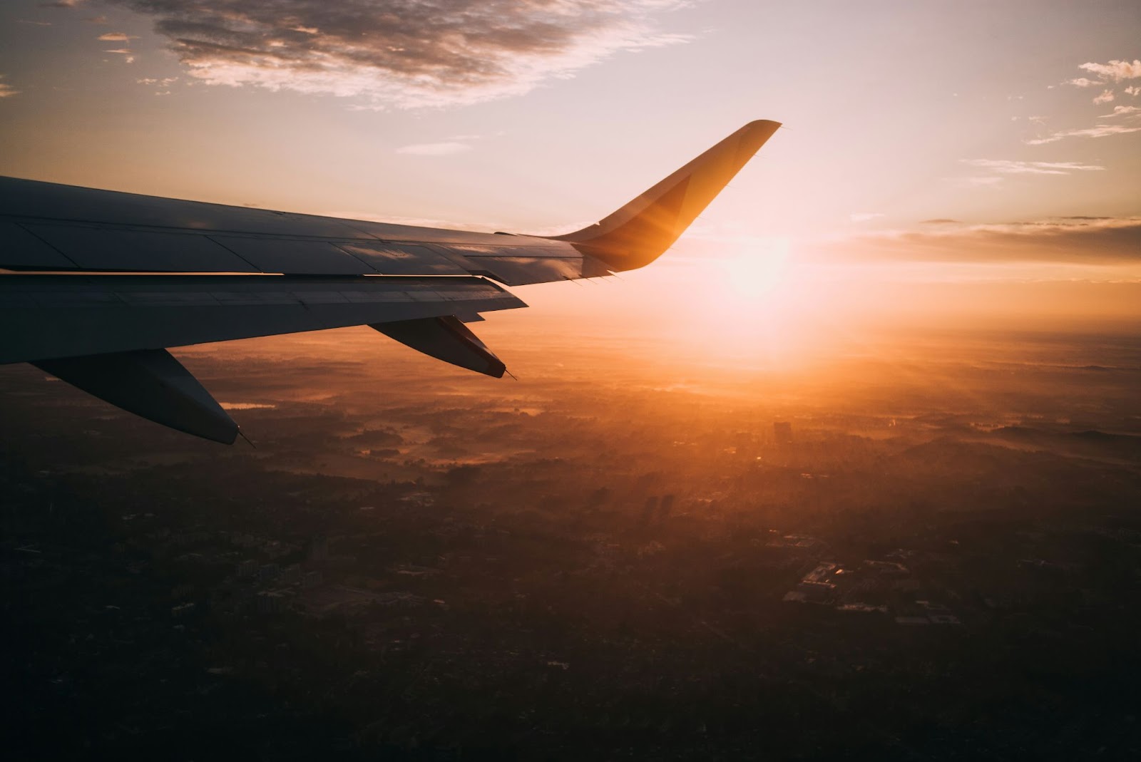 The view of an airplane wing out the window at sunset