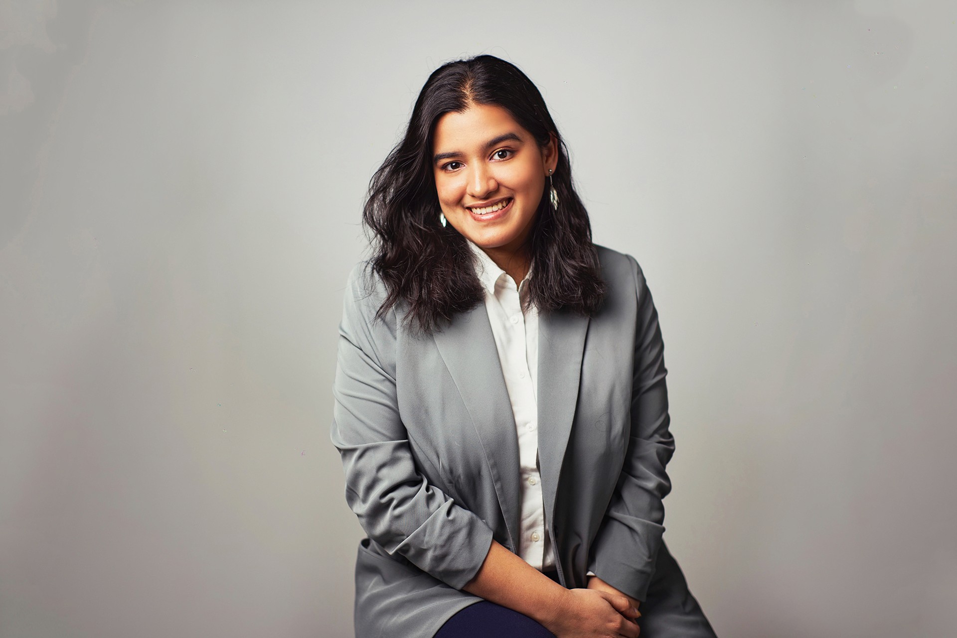 smiling girl with brown hair wearing a gray blazer jacket