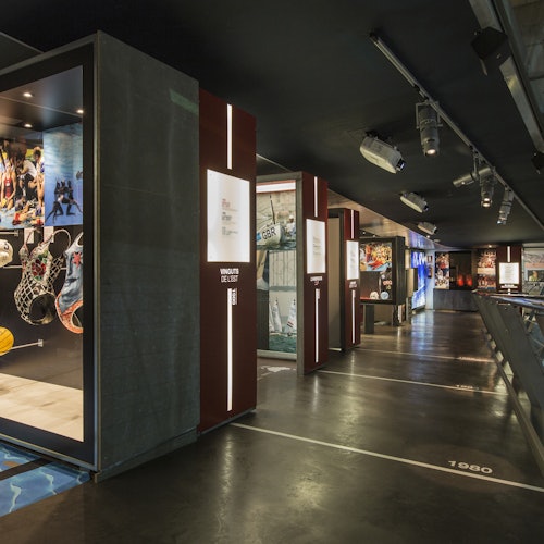Sala espositiva con segnaletica temporale sul pavimento, vetrine illuminate e vari pannelli informativi.