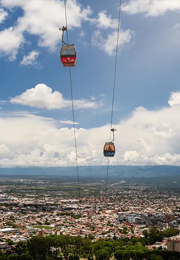 Teleférico urbano sobre a cidade, com cabines suspensas e vista panorâmica da região ao fundo