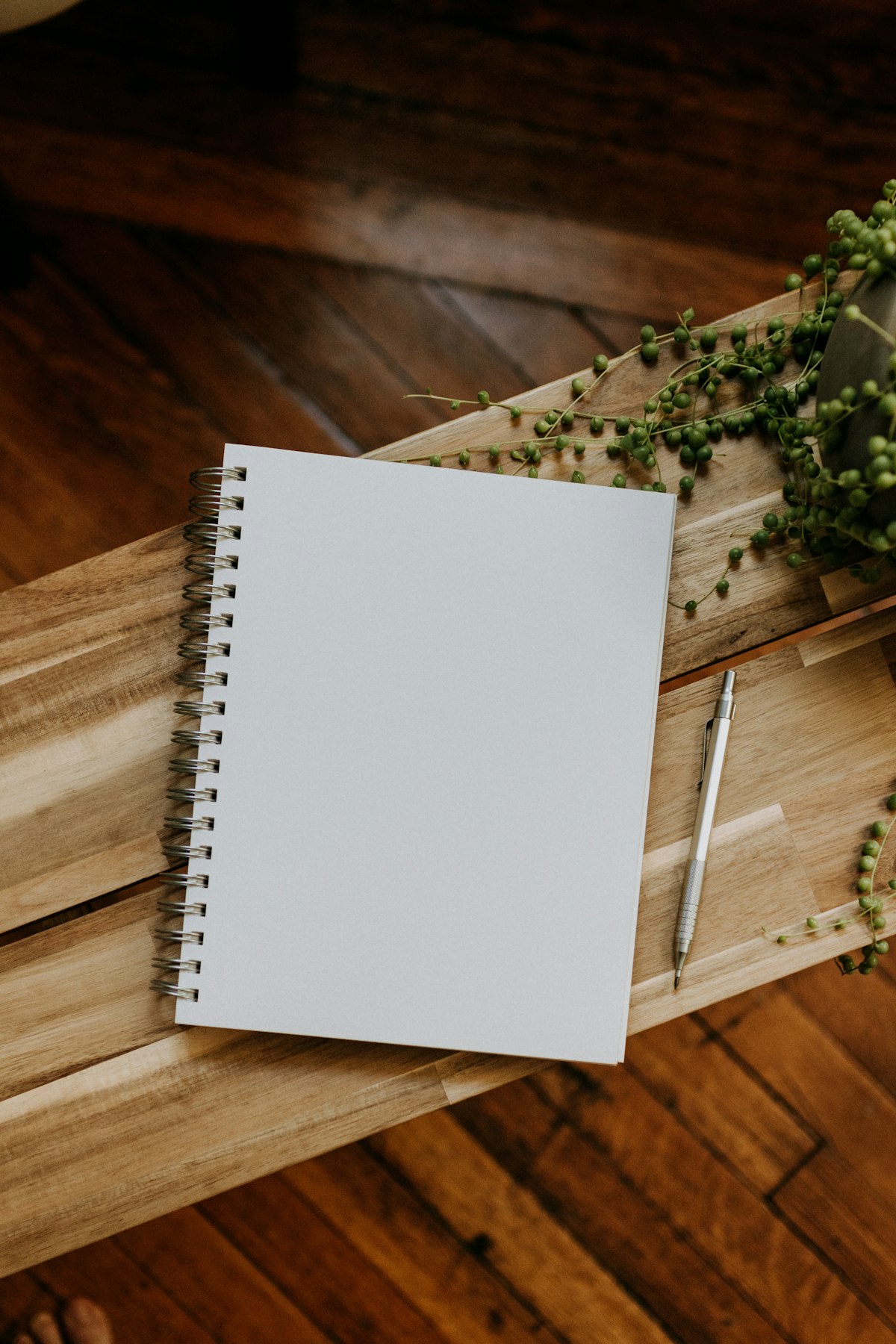Cuaderno abierto en blanco y un bolígrafo sobre una mesa de madera