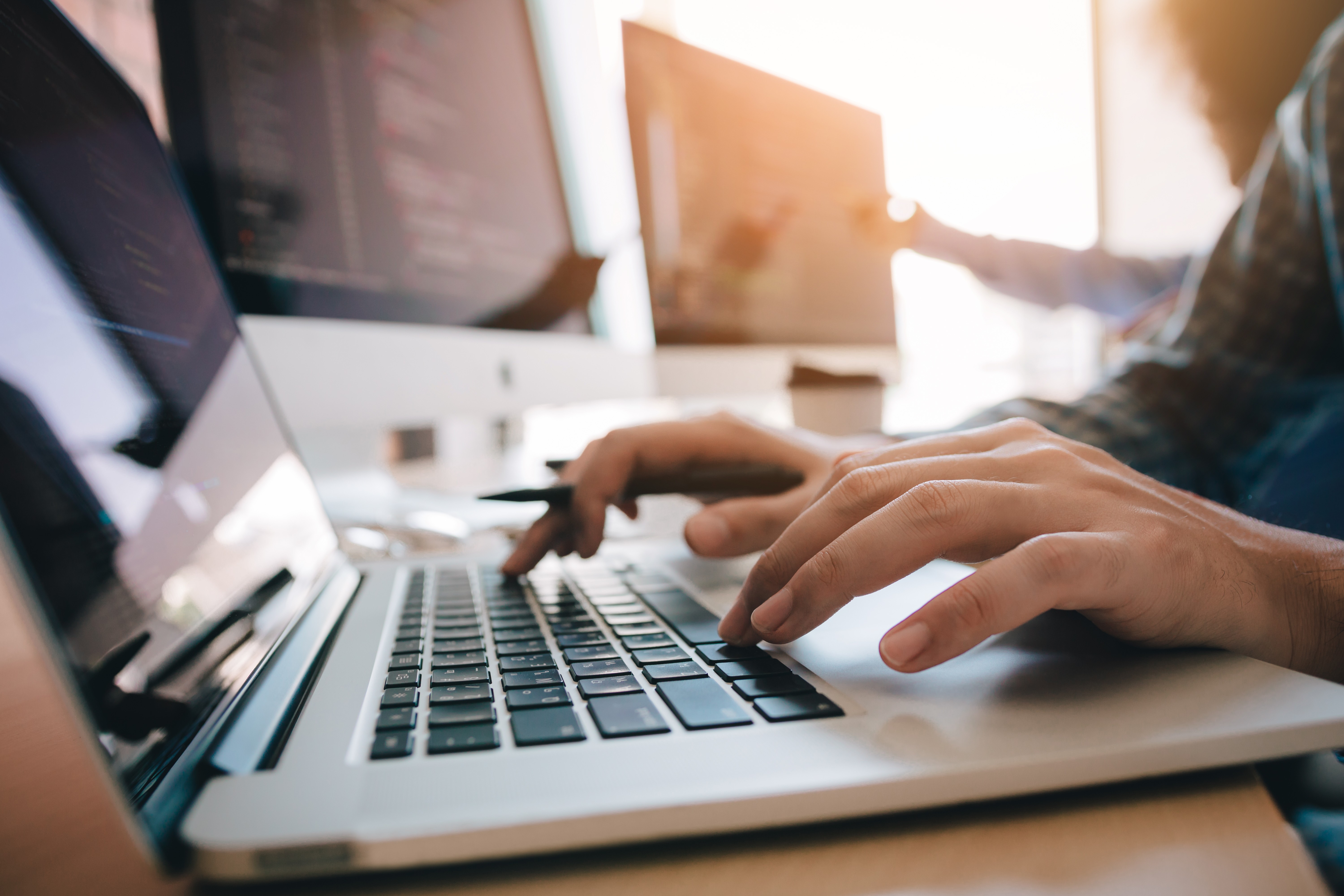 Image of Close-up of hands coding or working on a website in a modern workspace