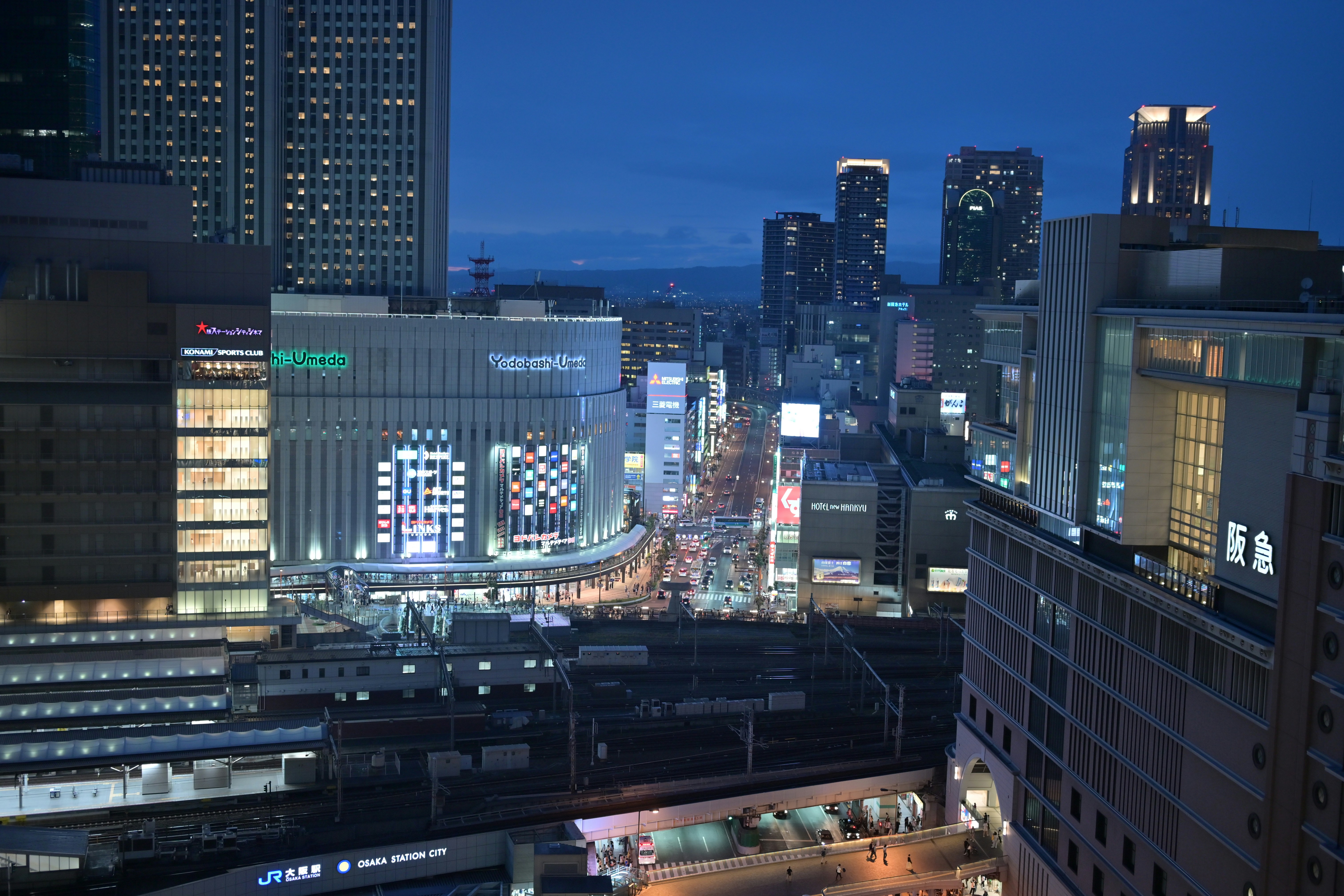 Modern living room with abstract art, beige sectional sofa, indoor plants, and large windows.