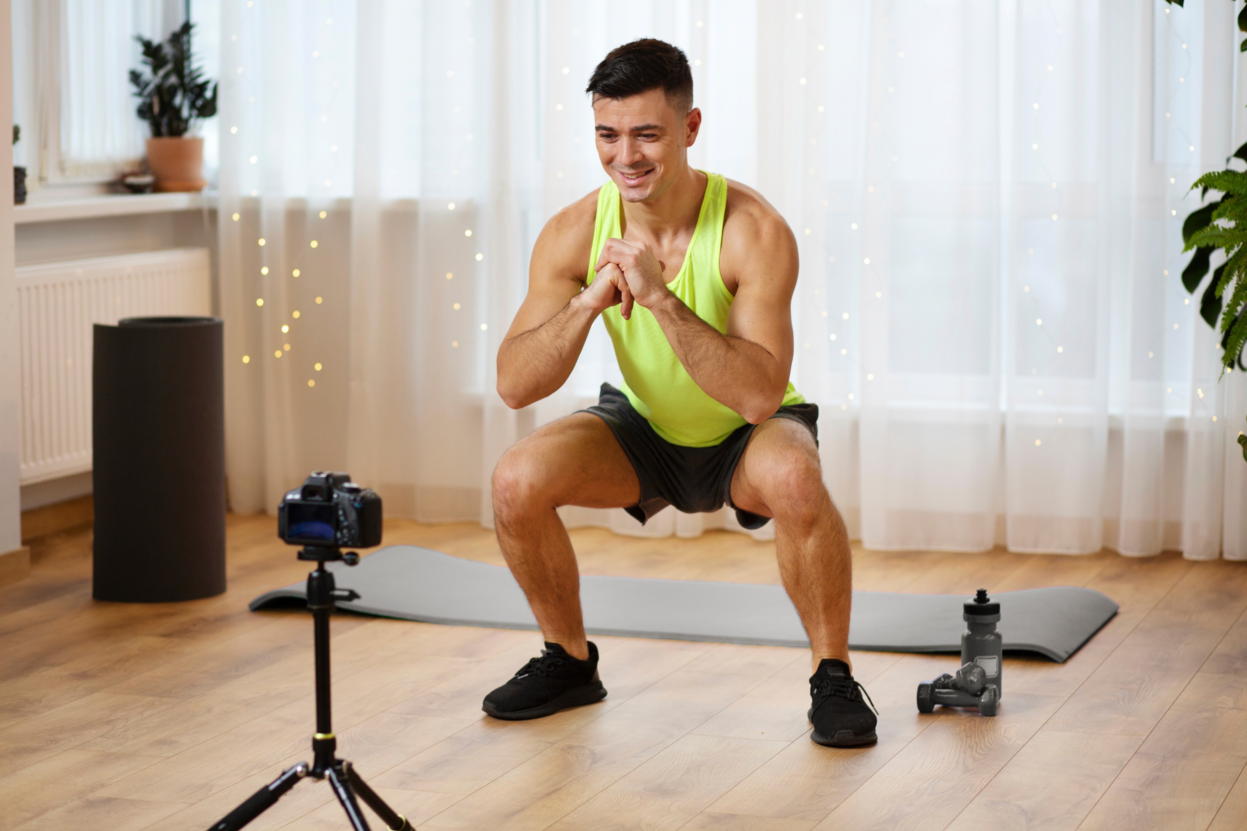 Man doing squats in front of a camera during a home workout.