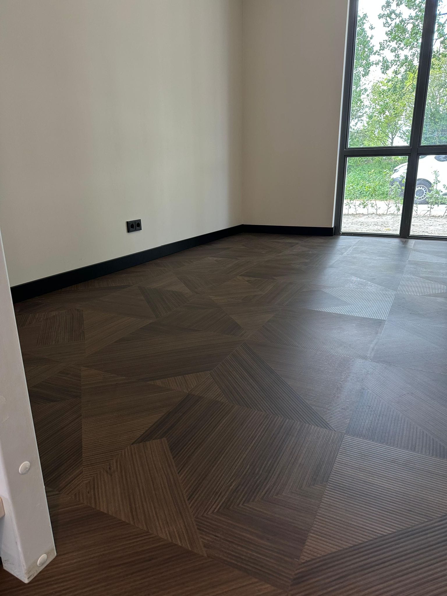 Donkere PVC-vloer met zwarte plinten in een lege ruimte.