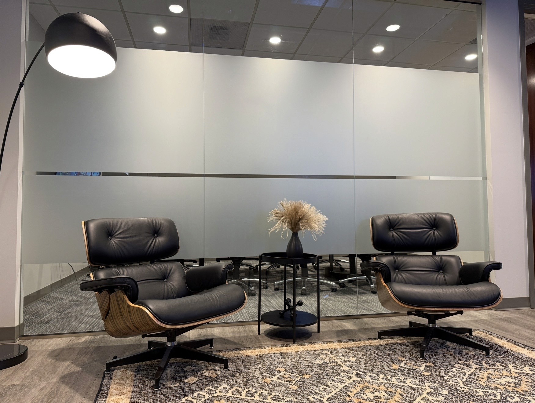 Pair of leather lounge chairs with wood shells, patterned rug, and frosted glass at Sage Mountain Offices
