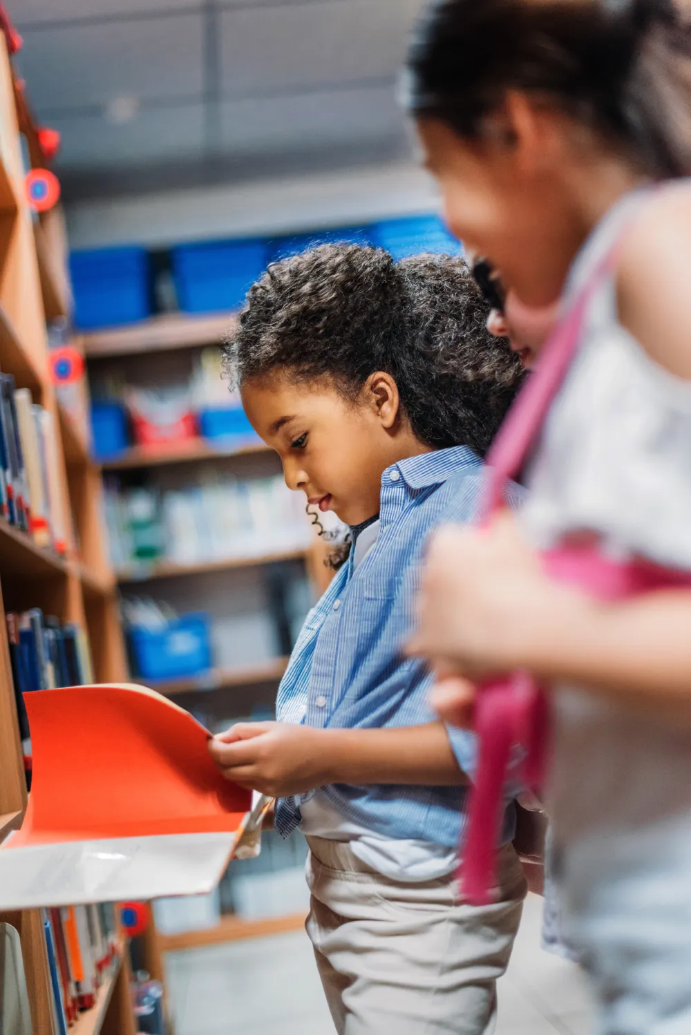 two girls looking at books in a library