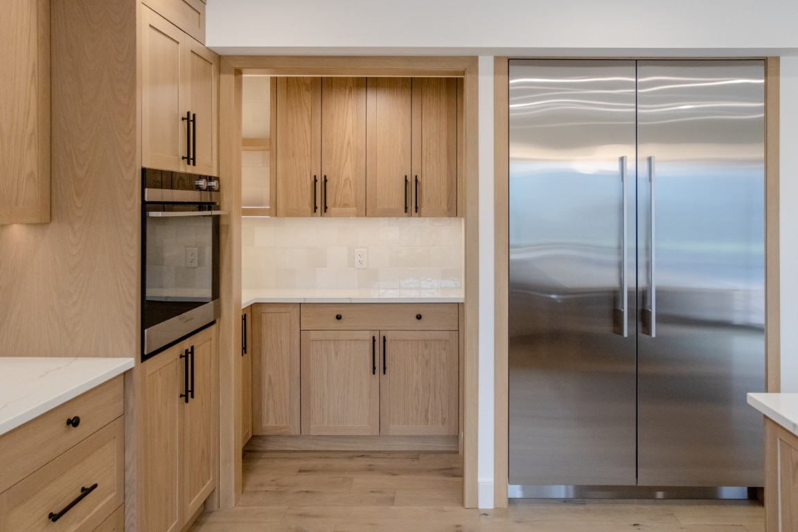 Image of Modern kitchen interior with wooden cabinets, stainless steel appliances, and marble countertops by KHD Homes.