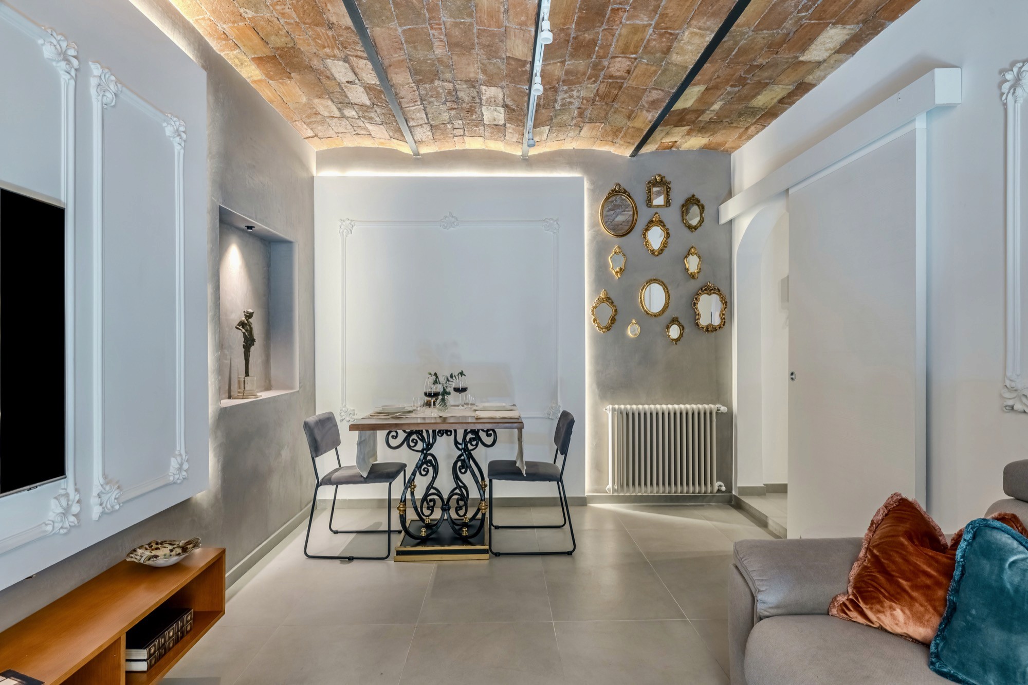 Salone panoramico con TV, divano letto, specchi dorati e mattoni in cotto a Roma Segreta