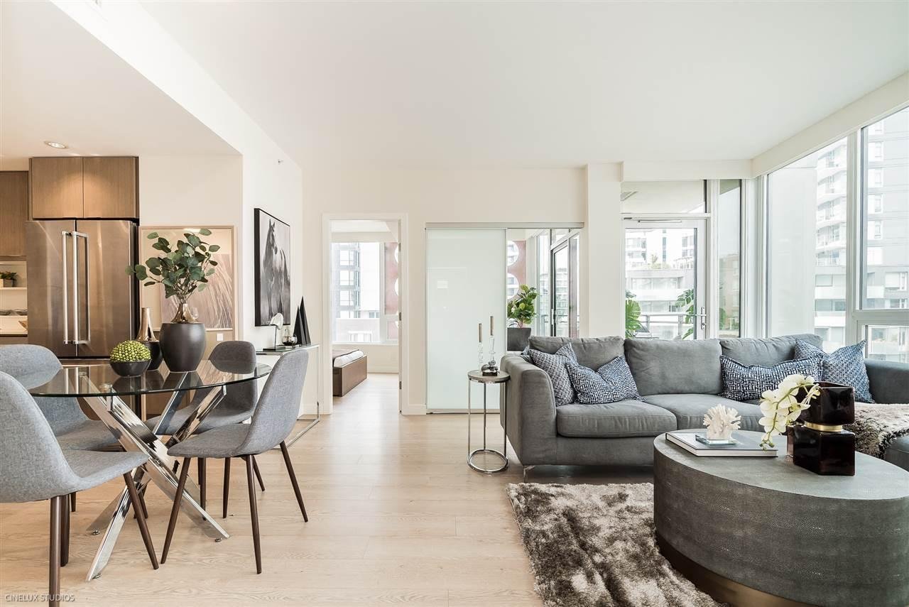 A modern, airy living room with large windows, stylish furniture, and a dining area in a bright, neutral color scheme.