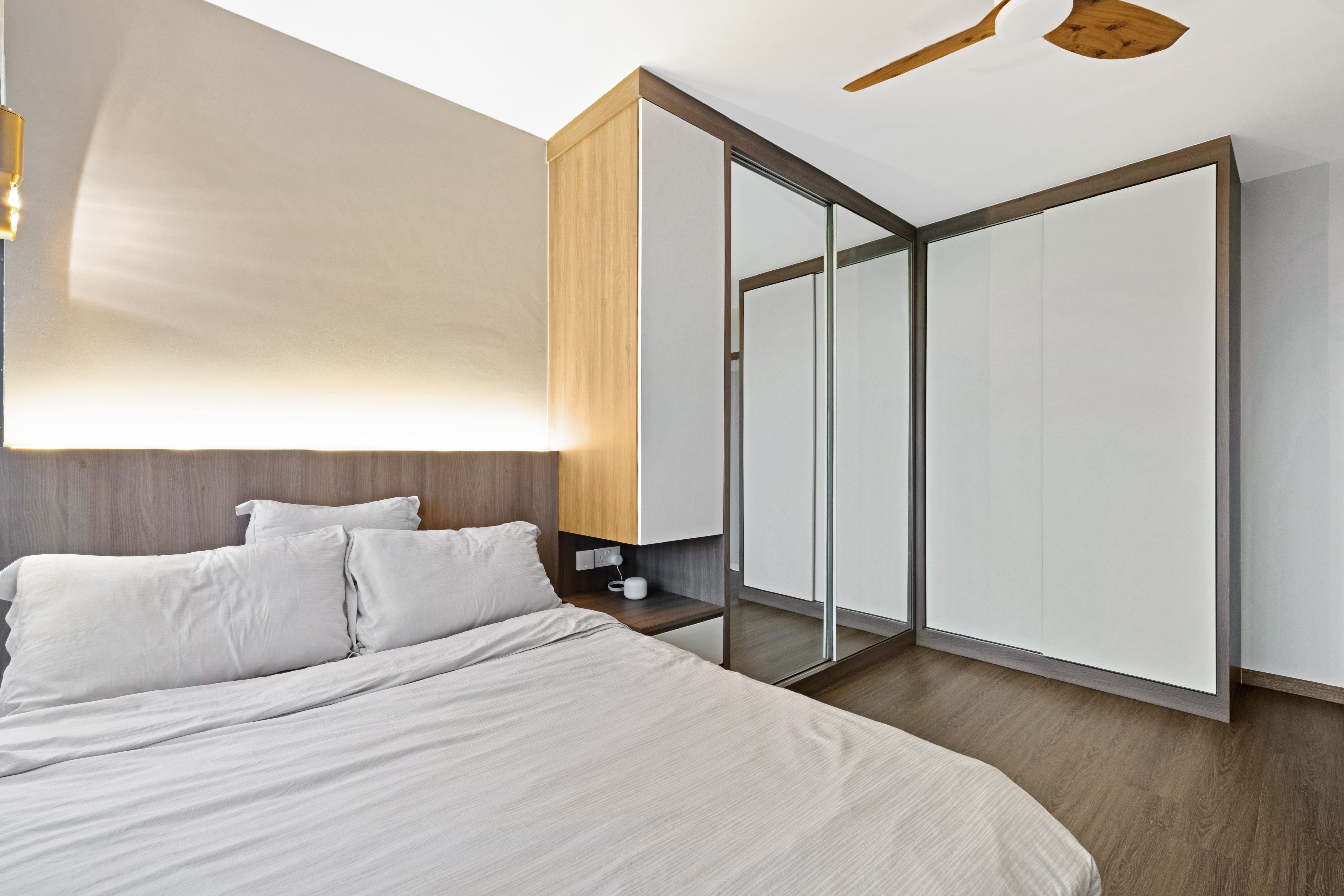 Cozy bedroom corner featuring an upholstered bed, wood-accented built-ins, and soft cove lighting that creates a calming atmosphere.