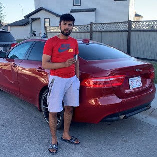 Customer holding a newly programmed car key next to a Jaguar after on-site car key service