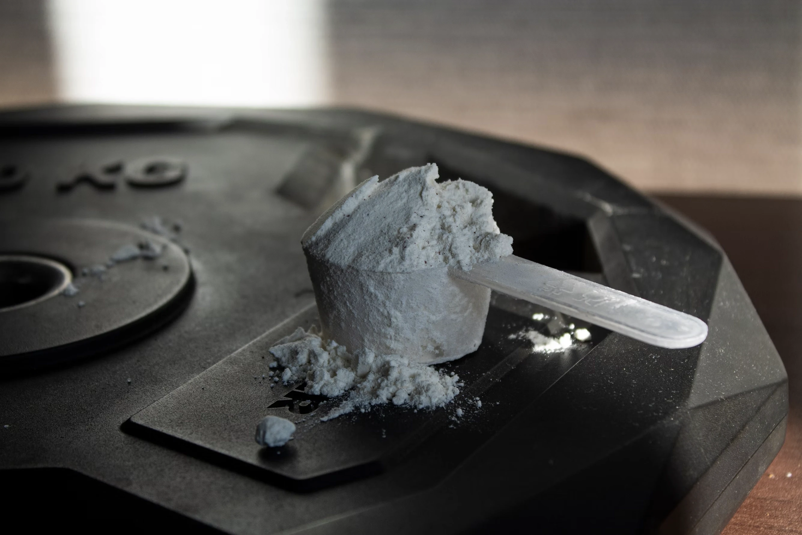 overflowing scoop of creatine monohydrate sitting on top of plate weight