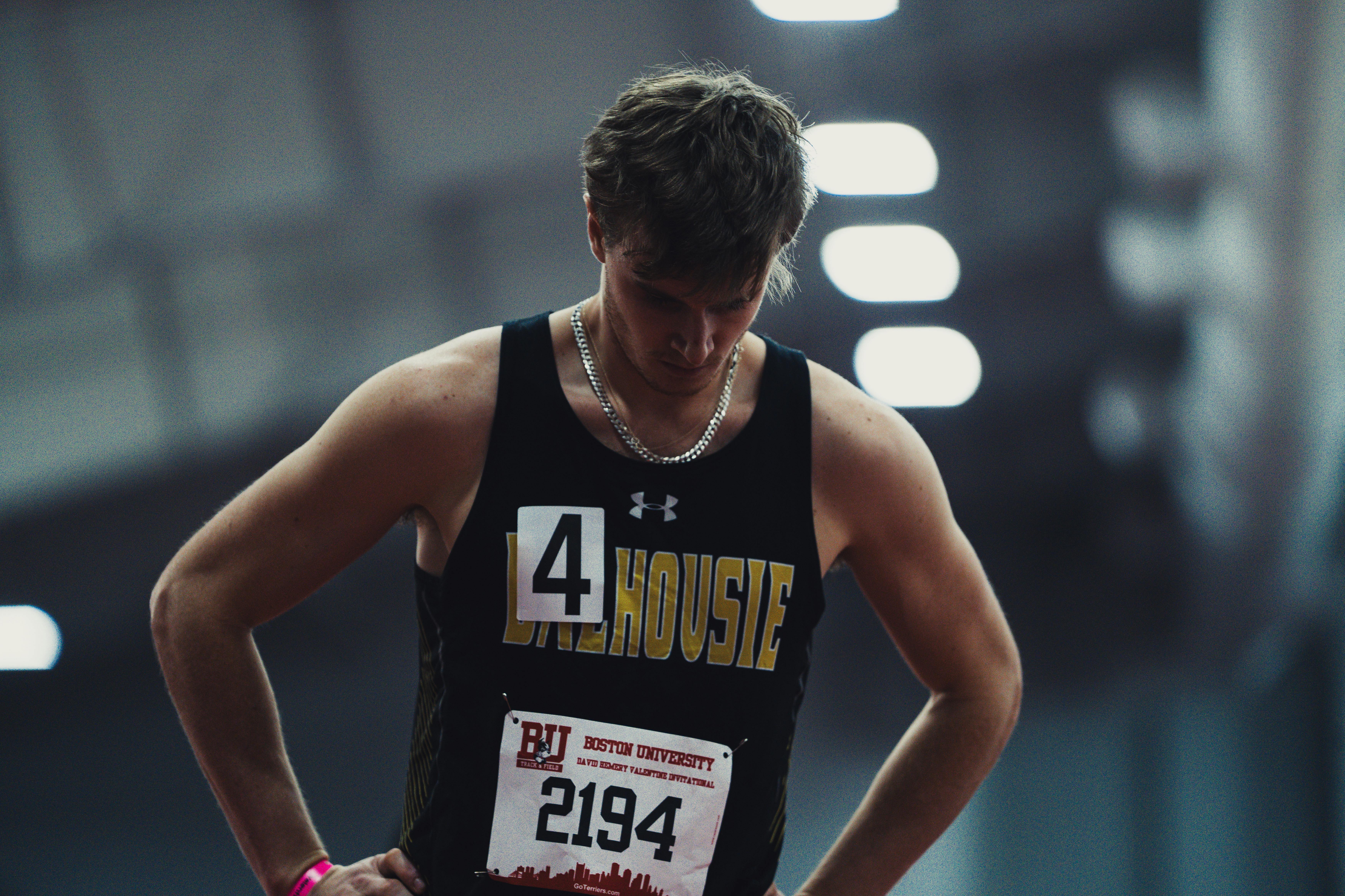 White male in track and field uniform with head down