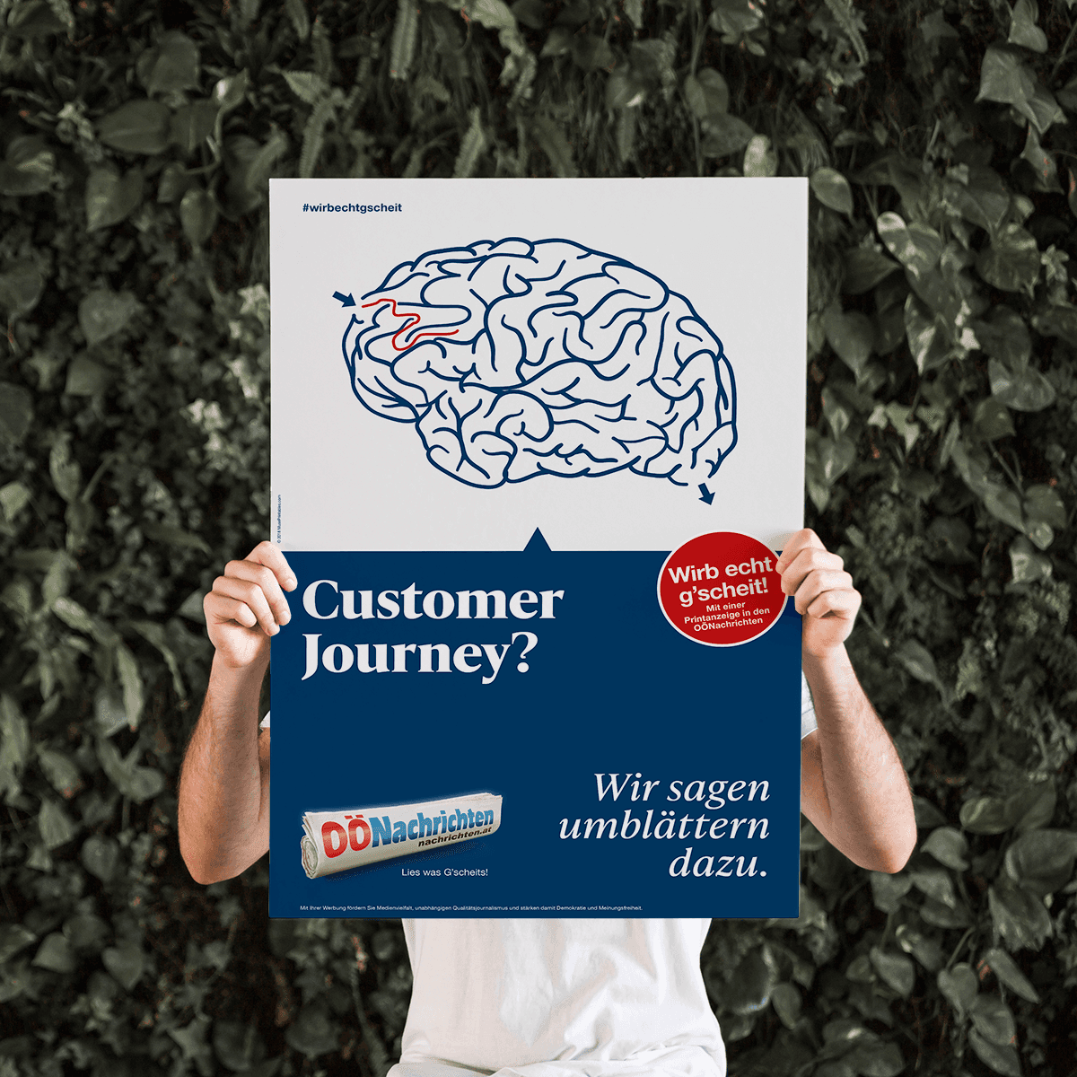Eine Person hält ein OÖNachrichten-Plakat mit einer Gehirnzeichnung und dem Text „Customer Journey? Wir sagen umblättern dazu.“
