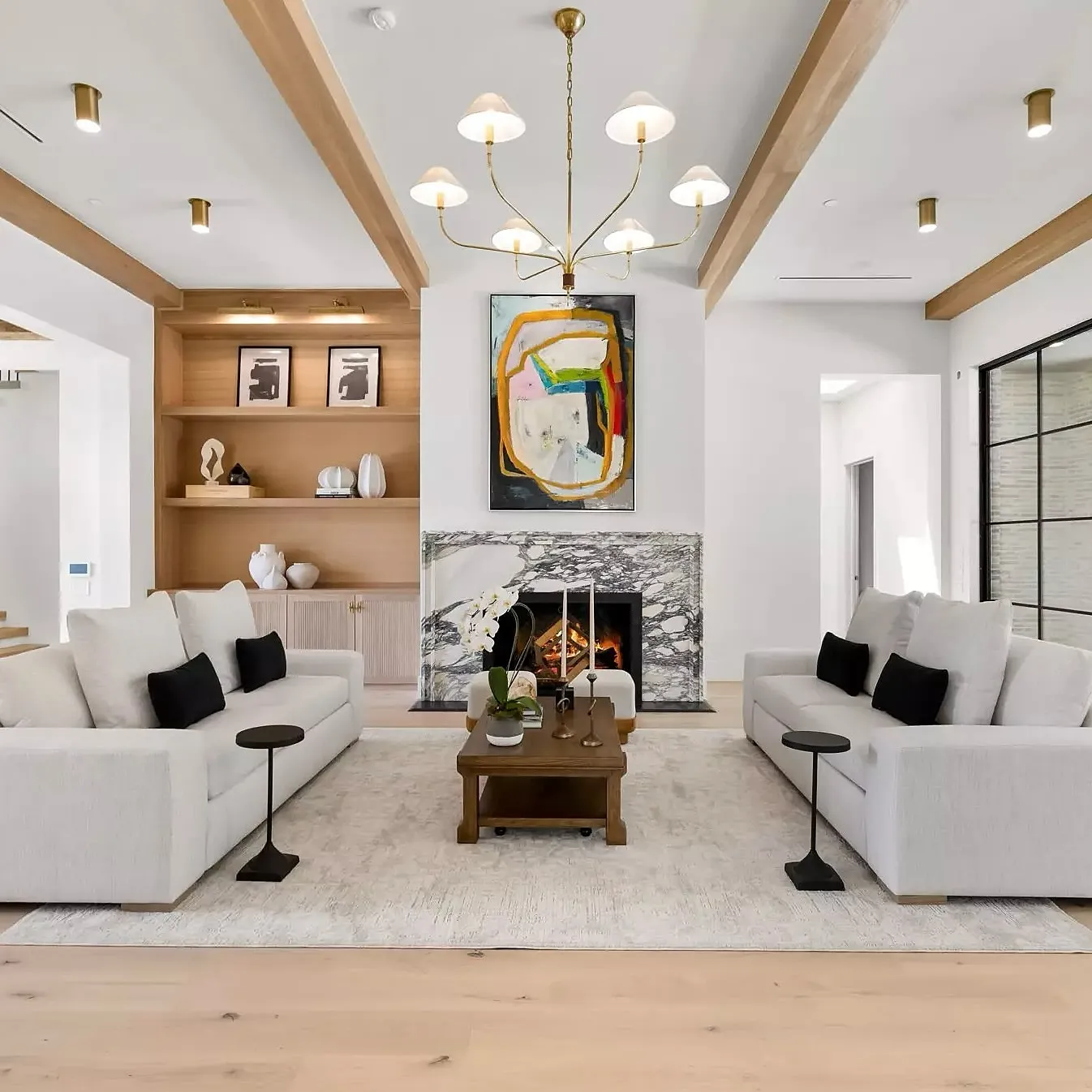 A modern living room with white sofas, a coffee table, and artwork on the walls.
