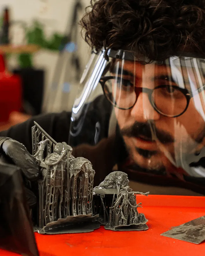 A man using a 3D printer to create a resin miniature from Loot Studios.